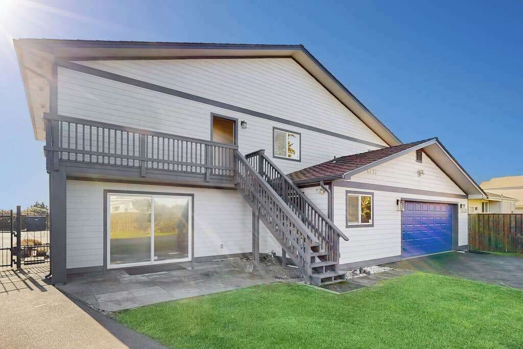 Ein zweistöckiges Haus mit einem überdachten Balkon, einer Garage und einer Treppe, die zu dem oberen Stockwerk führt.