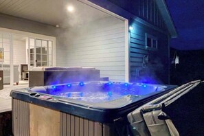 A hot tub with steam rising, surrounded by a wooden deck and a house with a covered patio. - Mojo's Dojo - Unique Coastal Hideaway with a Fun, Relaxed Vibe (McKinleyville)