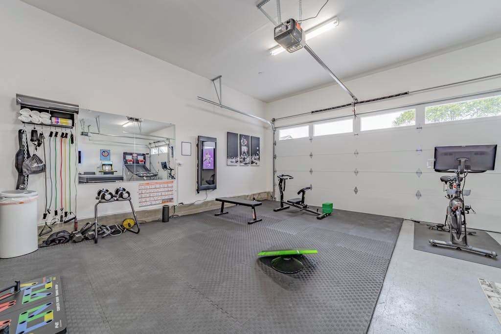 Ein Fitnessraum mit Trainingsgeräten, einem Spiegel und einem Fenster.