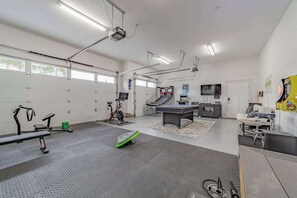 A gym with exercise equipment, a ping pong table, and a television. - Mojo's Dojo - Unique Coastal Hideaway with a Fun, Relaxed Vibe (McKinleyville)