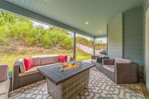 An outdoor patio area with a fire pit, wicker furniture, and a view of the backyard. - Mojo's Dojo - Unique Coastal Hideaway with a Fun, Relaxed Vibe (McKinleyville)
