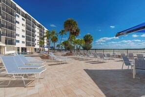 A rooftop pool area with sun loungers and palm trees, overlooking a clear blue sky. - ⛱️ Coastal Views | Beachfront Location | Paradise Point–Carlos Pointe #213 🌊 (Fort Myers Beach)