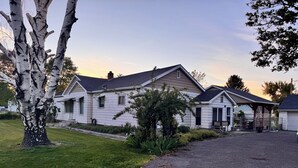 A two-story house with a driveway leading to the entrance, surrounded by a well-maintained lawn and trees.
