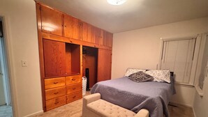 A bedroom with a bed, a bench, a wardrobe, and a window.
