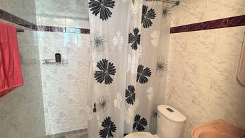 A bathroom with a shower curtain, toilet, and sink.