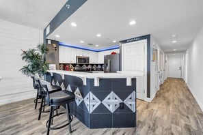 Une cuisine moderne avec des meubles blancs, un pare-feu noir et blanc et un îlot central doté de tabourets de bar.
