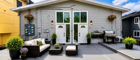 A residential building with a covered patio area featuring outdoor furniture and potted plants.