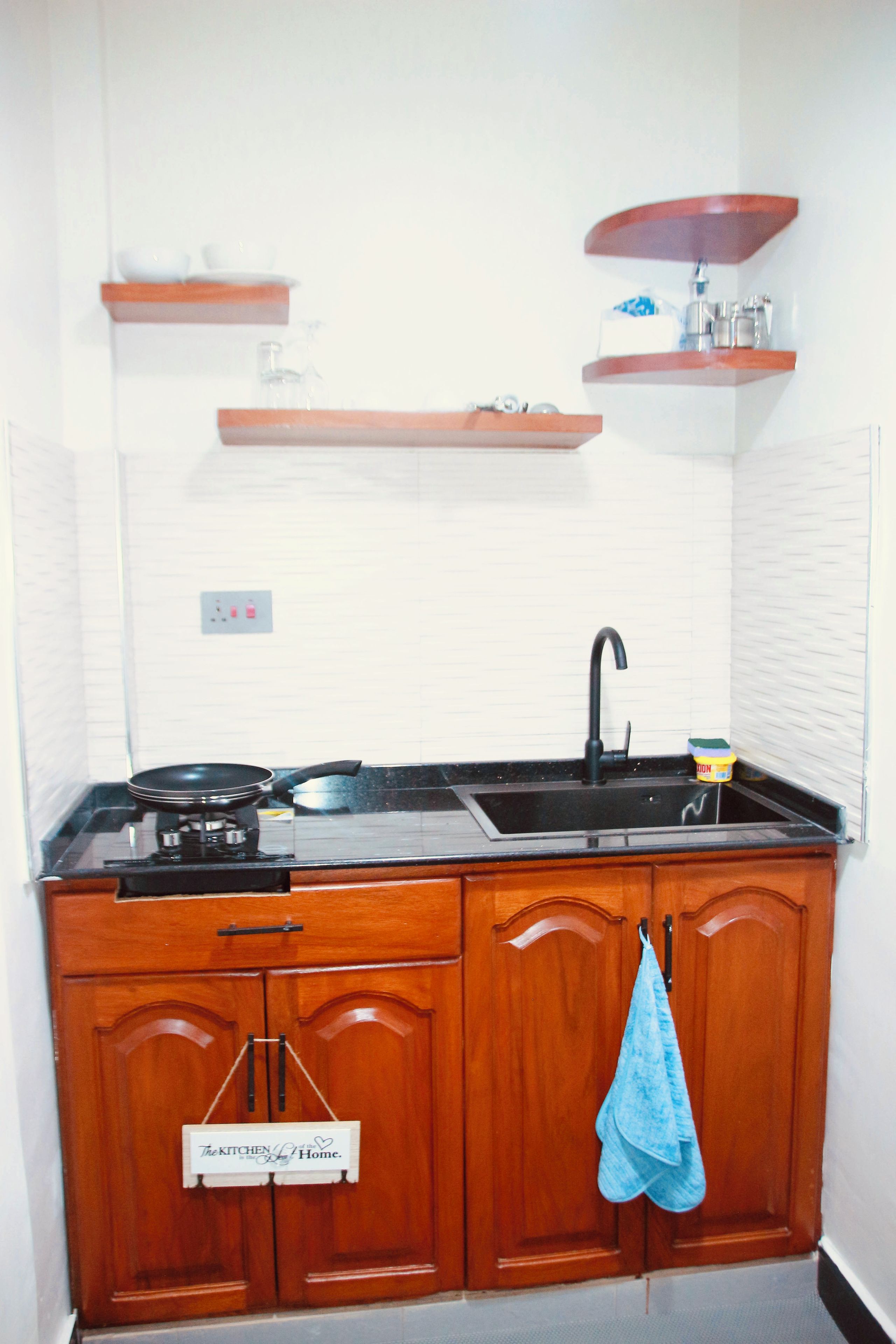 Una cocina con armarios de madera, encimera negra, un fregadero y una estufa.