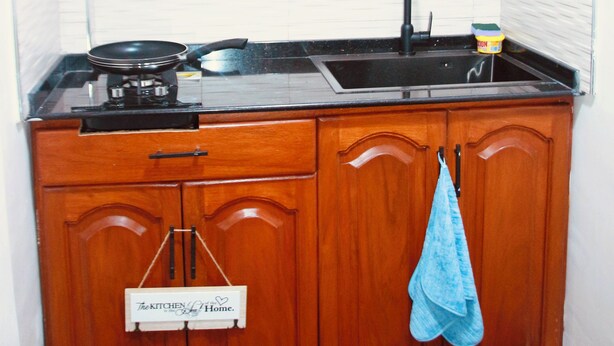 Una cocina con armarios de madera, encimera negra, un fregadero y una estufa.