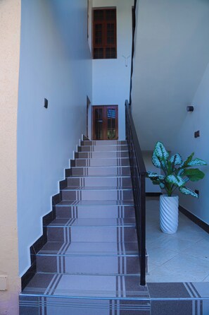 A staircase with patterned steps leading to a door with a window. - Ken Homestay (Arusha)