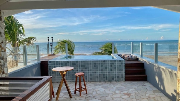 A balcony with a view of the ocean, a small pool, and two wooden stools. - Uba House in Icaraizinho/CE - Beachfront - infinity pool - right on the sand (Icarai)