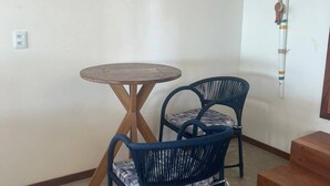 A corner room with a round wooden table and two blue wicker chairs. - Uba House in Icaraizinho/CE - Beachfront - infinity pool - right on the sand (Icarai)
