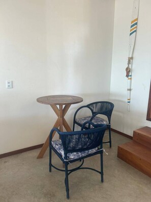 A corner room with a round wooden table and two blue wicker chairs. - Uba House in Icaraizinho/CE - Beachfront - infinity pool - right on the sand (Icarai)