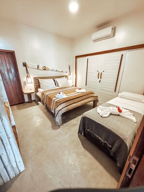 A hotel room with a bed, a wardrobe, a bedside table, and an air conditioning unit. - Uba House in Icaraizinho/CE - Beachfront - infinity pool - right on the sand (Icarai)
