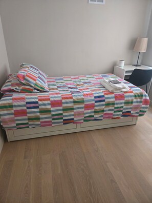 A single bed with a striped bedspread, a pillow, and a folded towel. There is a desk with a chair and a lamp to the right. - Wonderful townhome East Lakeview near cubs 5 min walk to lake in vibrant Chicago (Chicago)