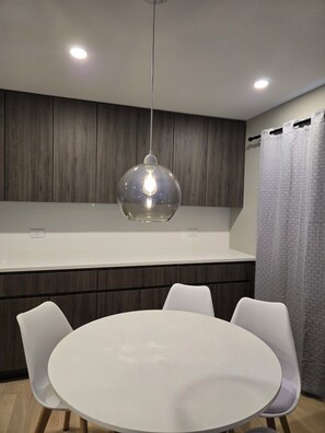 A modern kitchen with a round dining table, white chairs, and pendant lighting. - Wonderful townhome East Lakeview near cubs 5 min walk to lake in vibrant Chicago (Chicago)