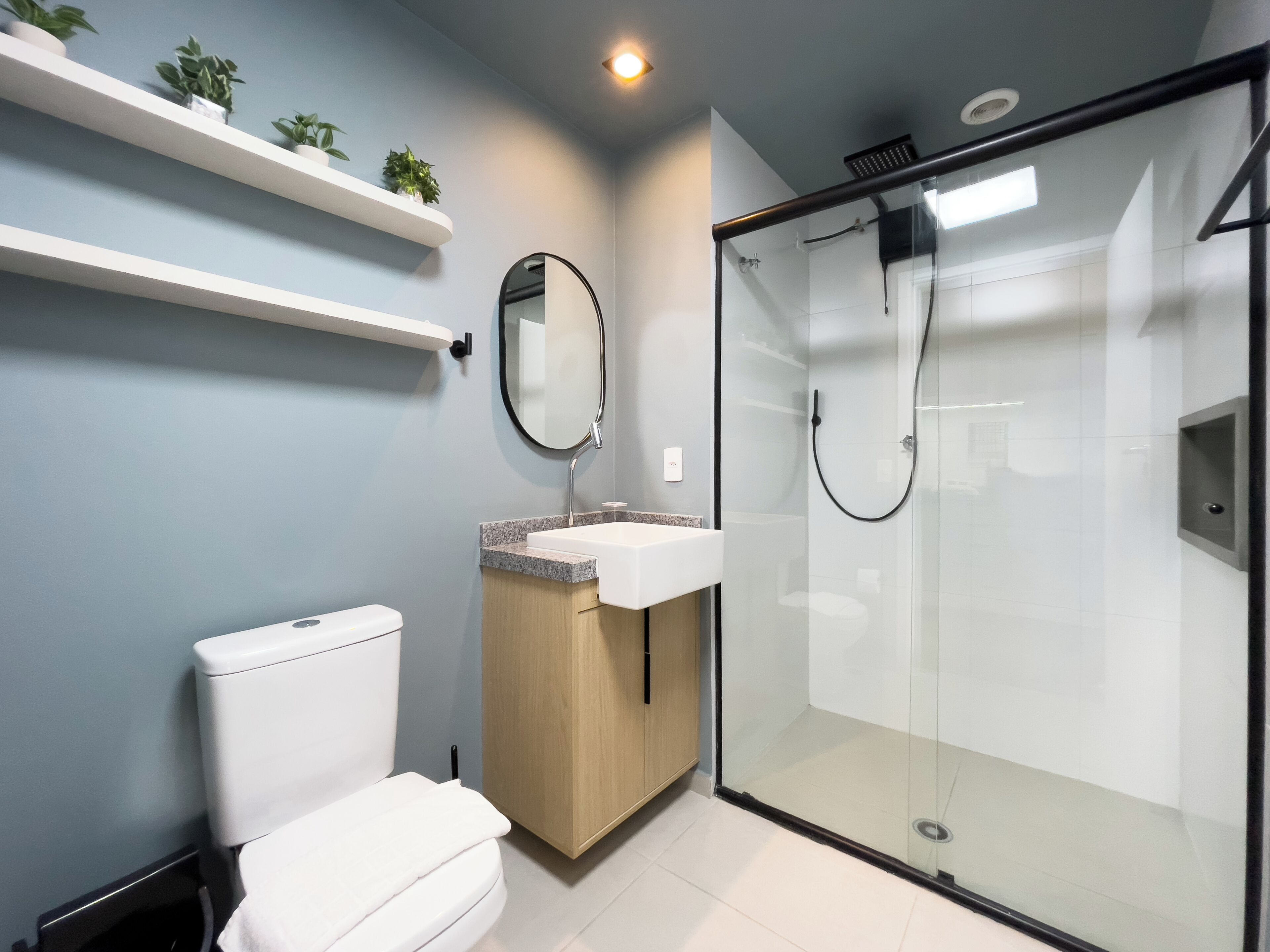 Un baño moderno con inodoro, lavamanos y ducha con mampara de vidrio.
