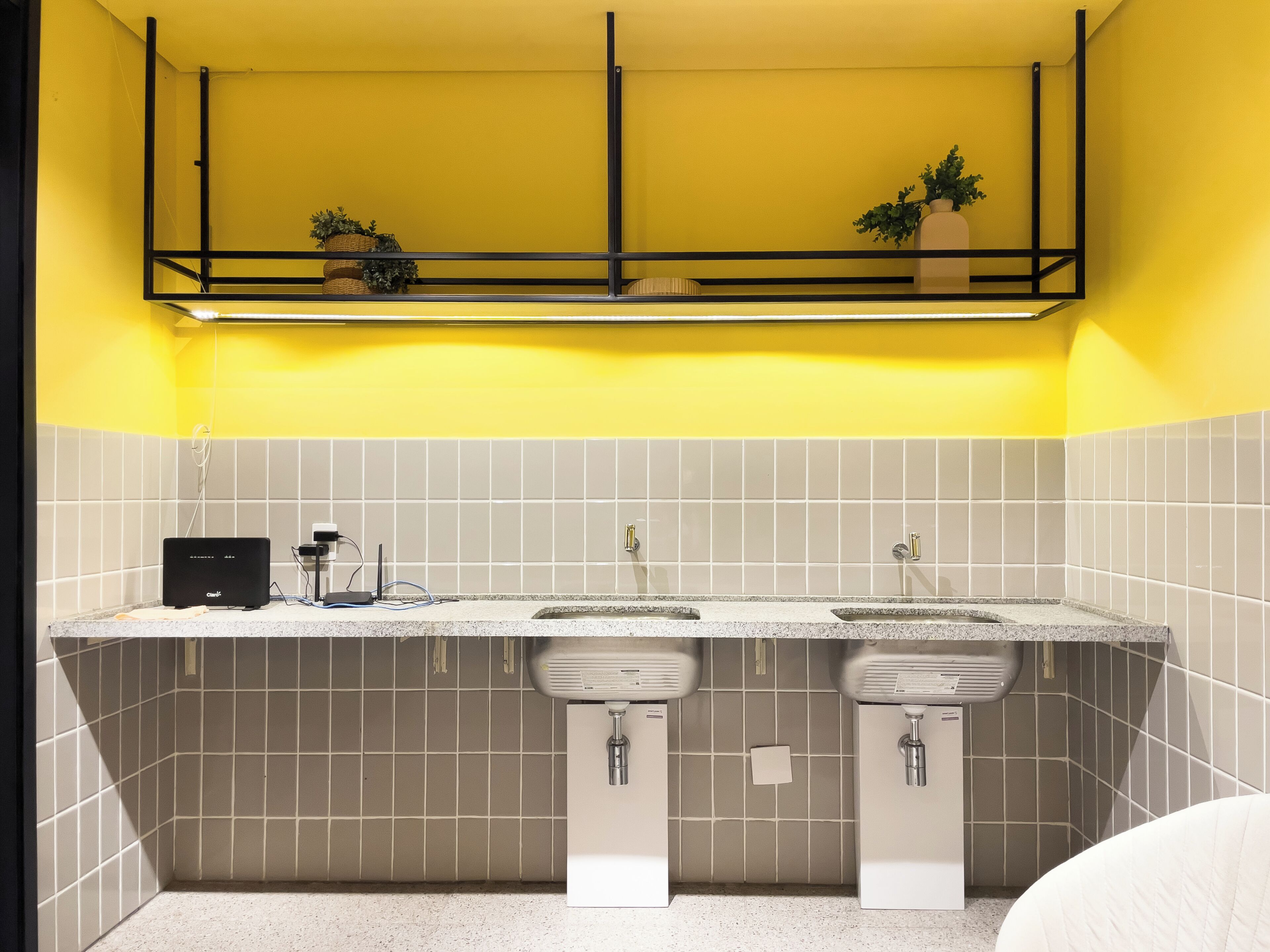 A bathroom with two sinks, a towel rack, and a shelf above the sinks.