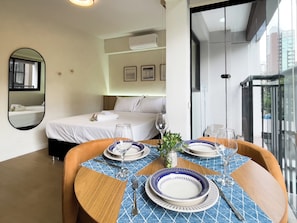 A hotel room with a bed, a dining table set with plates and cutlery, and a view of the city through the window. - OY Campo Belo (São Paulo)
