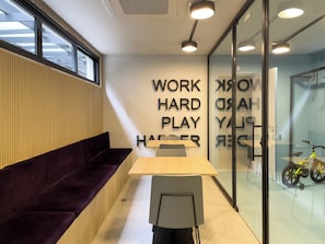 A modern office space with a wooden table, a purple sofa, and a glass wall with motivational text. - OY Campo Belo (São Paulo)