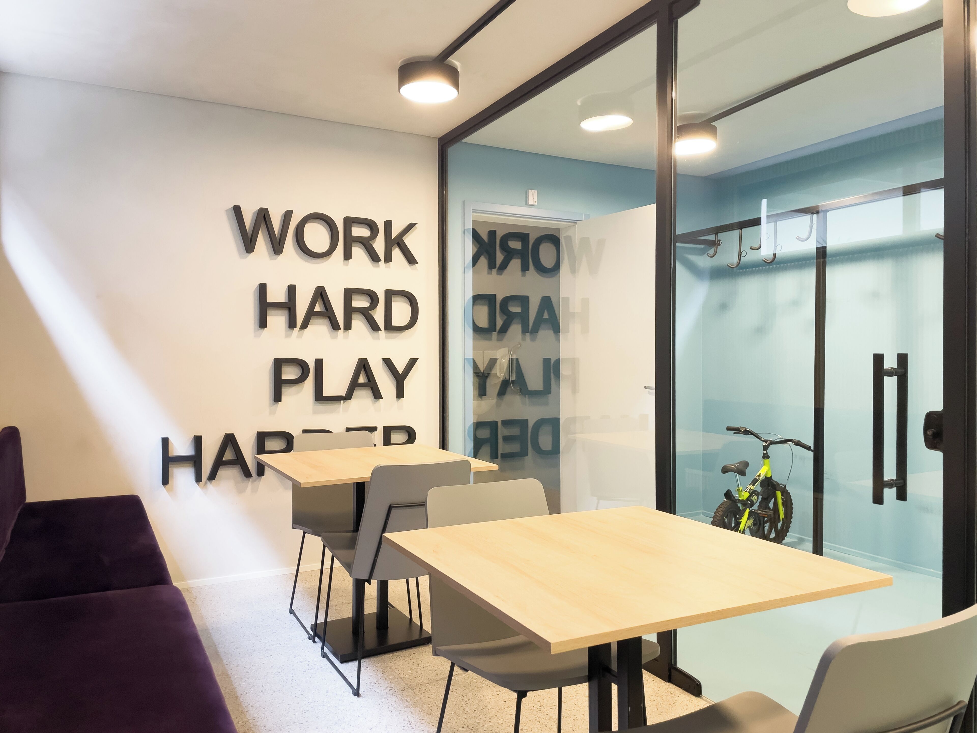 A modern office space with a glass wall, a wooden table, and a bicycle.