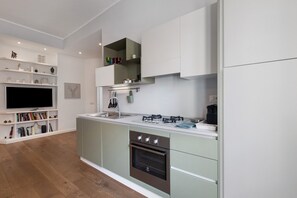 Eine moderne Küche mit Einbauofen, Kochfeld und Flachbildfernseher.
