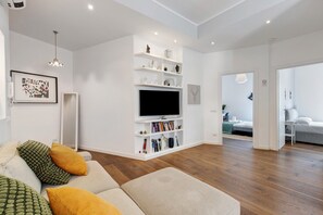 Un salon moderne avec un canapé, un téléviseur et une étagère blanche.