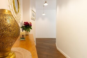 Ein Flur mit Holzboden, einer dekorativen Messinglampe, einer Blumenvase und einer Pendelleuchte.