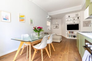 Ein zeitgemäßer Wohnraum mit Essbereich, einer Couch, einem Fernseher und einer Küchenzeile.