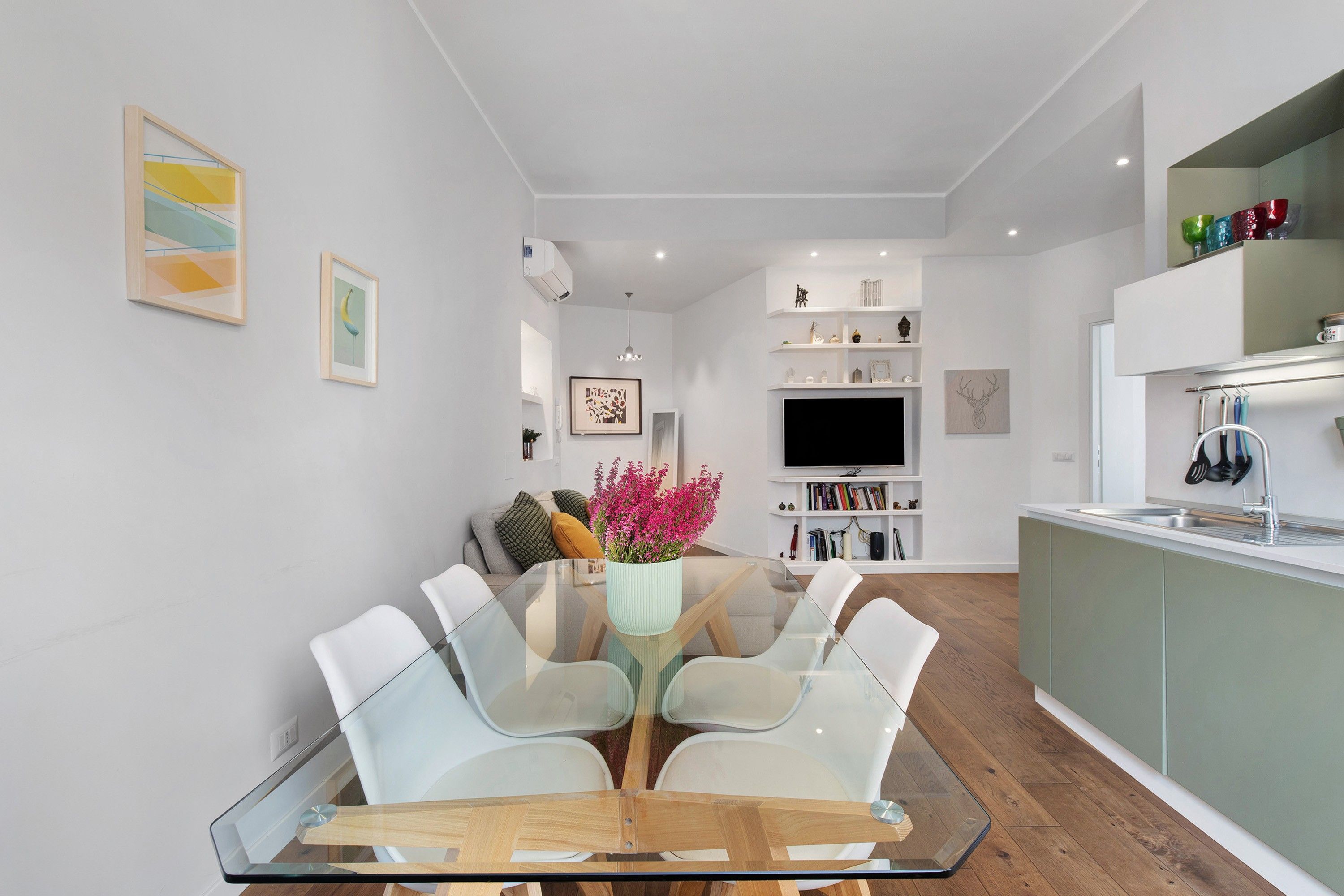 A modern kitchen with a built-in island, white cabinetry, and a flat-screen TV above the counter.