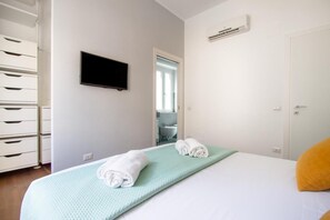 Ein Hotelzimmer mit einem Bett, einem Fernseher, einem durchgegangenen Tür einsehbaren Badezimmer und einer Kommode.