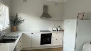 Eine moderne Küche mit weißen Schränken, einem Einbauofen, einem Geschirrspüler und einem Kühlschrank.