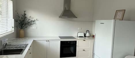 A modern kitchen with white cabinetry, a built-in oven, a dishwasher, and a refrigerator.
