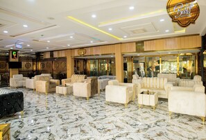 Um hall luxuoso com assentos macios, piso de mármore e um espelho grande refletindo o interior.