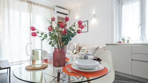 A dining area with a glass table, a vase with flowers, and a white plate. - Italianway Comfort - Panfilo Castaldi 23 (Milan)