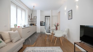 Ett modernt kök med matplats, en soffa och en TV.