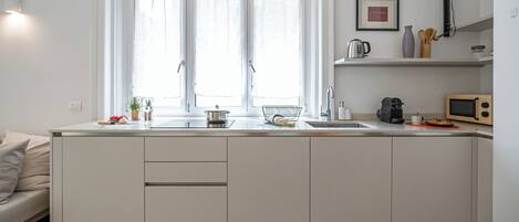 Una cocina moderna con un ventanal grande, un fregadero, un microondas y un hervidor.