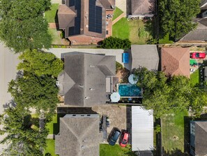 Zona residencial con piscina, varios coches y abundante vegetación.