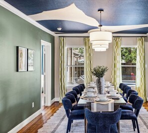Comedor con una mesa larga dispuesta para seis personas, rodeada de sillas tapizadas en azul oscuro.