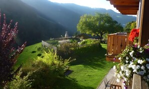 Ein Garten mit einer Holzkonstruktion, einem Weg und Blick auf Hügel.