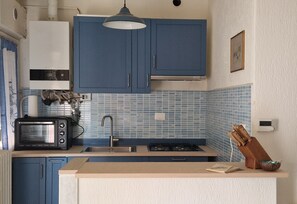 Eine kleine Küche mit blauen Schränken, einer Mikrowelle, einem Spülbecken und einem Gasherd.