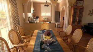 A dining area with a wooden table, wicker chairs, and a chandelier.