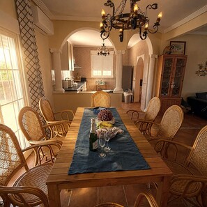 A dining area with a wooden table, wicker chairs, and a chandelier.