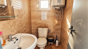 A compact bathroom with a sink, toilet, and a water heater.