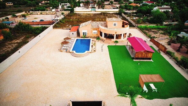 A residential property with a swimming pool, a covered patio, and a fenced yard.