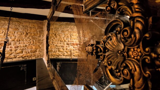 A room with stone walls, a fireplace, and ornate metalwork. - 1503 – Exceptional Suite for Two in the Heart of Historic Sarlat-France (Sarlat la Canéda)