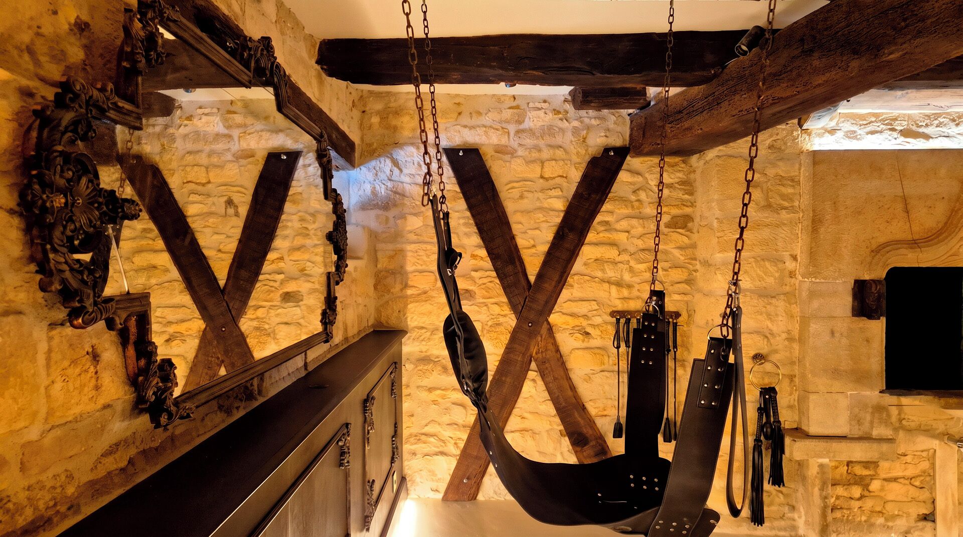 A rustic interior with exposed stone walls, wooden beams, and a hanging chair.