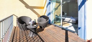 A balcony with wicker furniture and a bottle of wine, overlooking a bedroom with a bed and a desk. - Holiday Home 'Adosado Puerto Banús Relax' with Private Pool, Wi-Fi and Air Conditioning (Marbella)