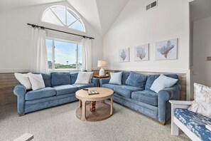 A living room with a sectional sofa, a round coffee table, and a window with curtains. - A-B-Ceas: Recently Renovated 5Br (Corolla)