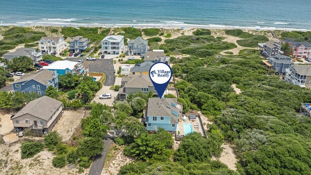 Zona residencial costera con casas, una playa y un anuncio de Village Realty.